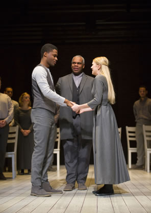 George and Emily in simple clothes face each other holding hands with Mr. Webb standing in the middle.